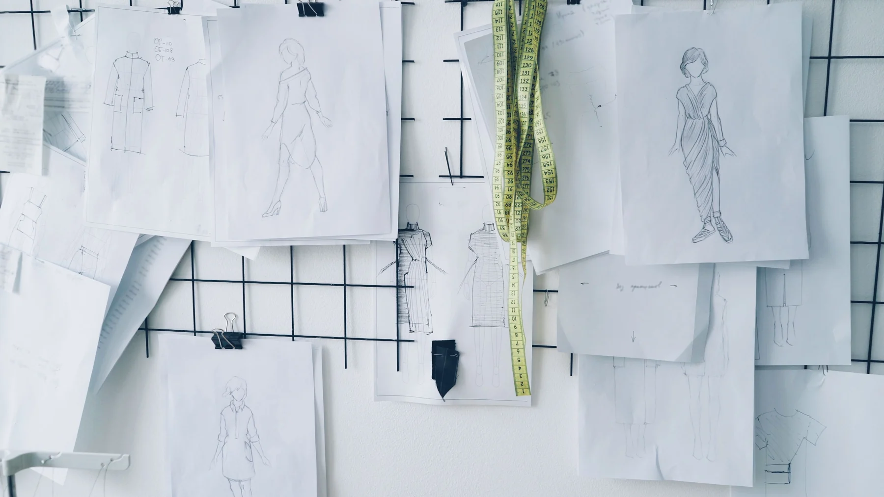 Fashion sketches and textile development notes on a studio wall